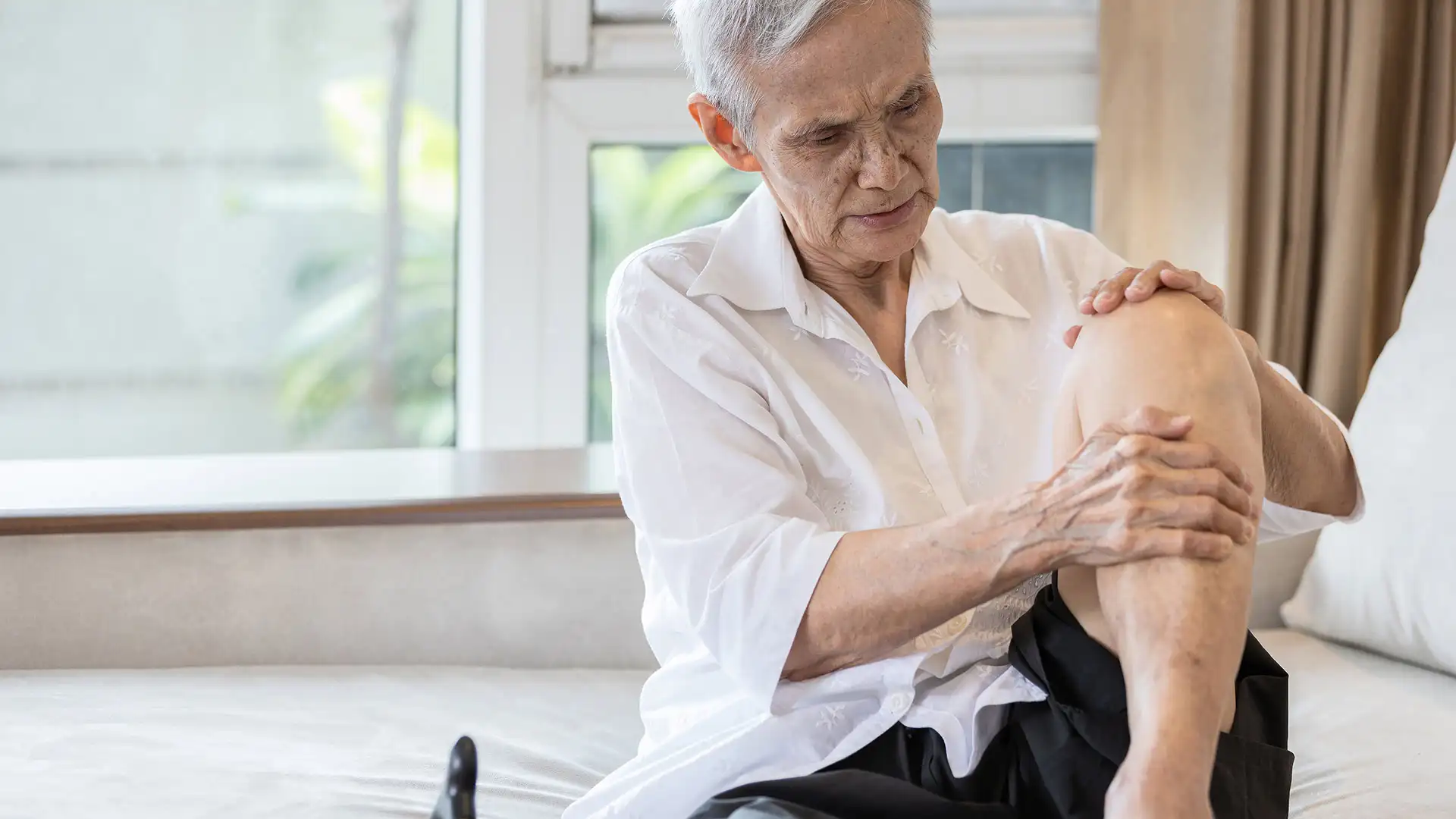 Elderly woman experiencing knee pain from arthritis