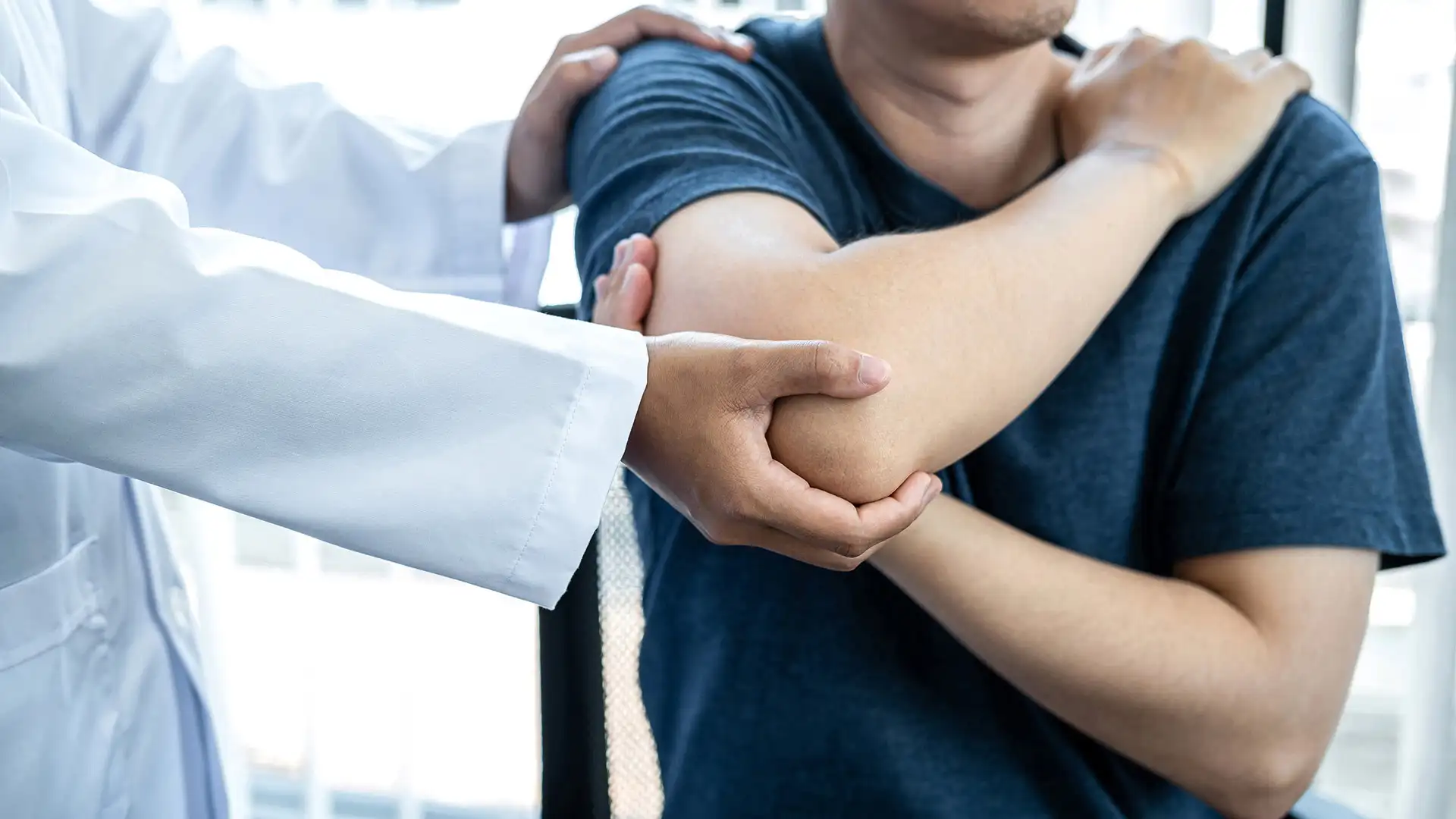 Physiotherapist performing shoulder rehabilitation therapy on patient