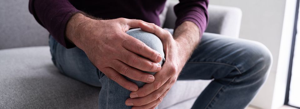 Photo of a man holding his knee in pain.