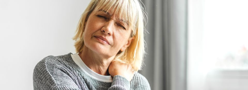 Person with either neck or shoulder pain trying to sooth it.