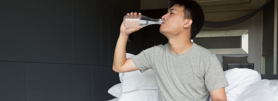 Someone drinking water and resting in bed after a PRP injection.